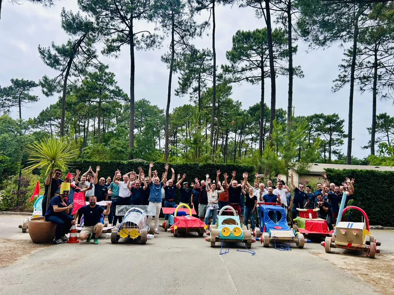 Une soixantaine de collaborateurs posent bras levés derrière leurs voitures en carton après un team building